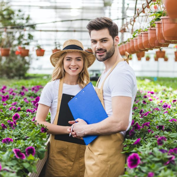 couple-of-gardeners-holding-clipboards-by-flowers-in-greenhouse.jpg