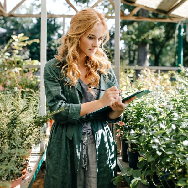 curly-girl-botanist-exploring-plants-in-greenhouse-woman-in-khaki-tunic-makes-notes-in-tablet-.jpg